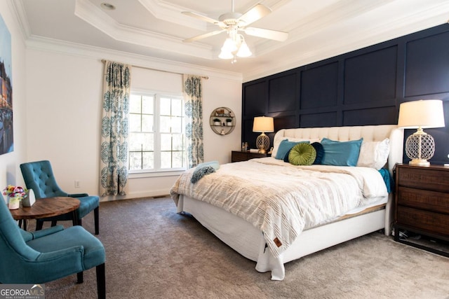 bedroom featuring a tray ceiling, ornamental molding, ceiling fan, and carpet