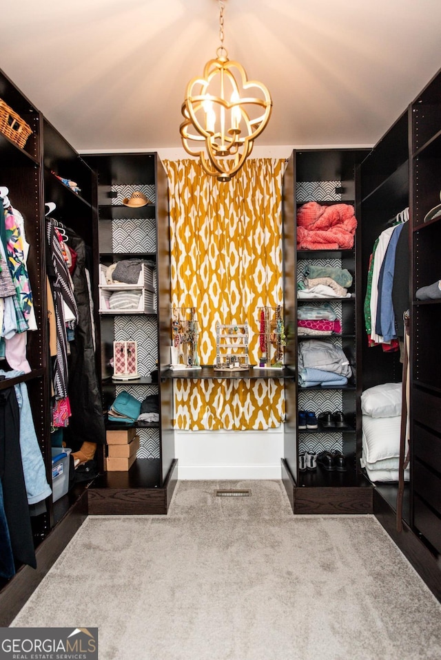 spacious closet with an inviting chandelier and carpet flooring