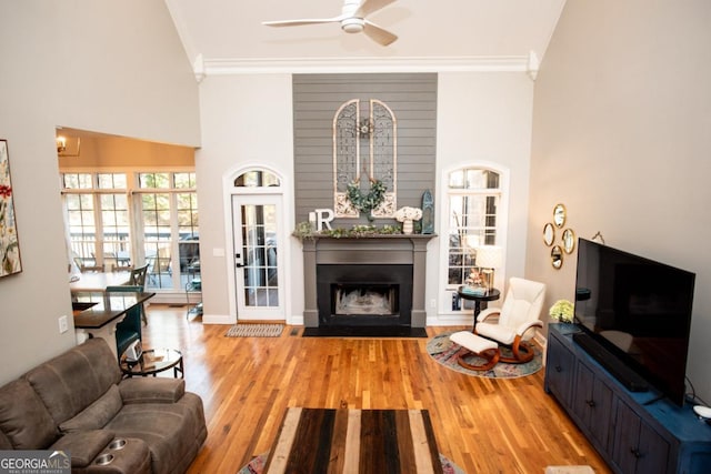 living room with ornamental molding, ceiling fan, and light wood-type flooring