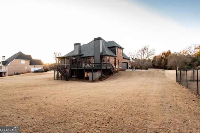 rear view of house with a wooden deck, a garage, and a sunroom