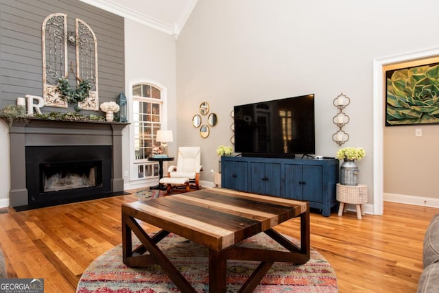 living room featuring hardwood / wood-style flooring, crown molding, and high vaulted ceiling