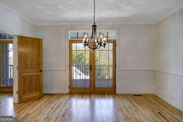 unfurnished dining area featuring ornamental molding, a notable chandelier, and light hardwood / wood-style floors