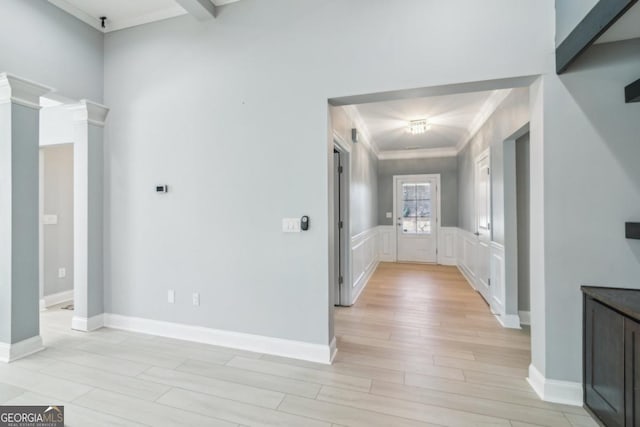 hall featuring decorative columns, crown molding, and light wood-type flooring