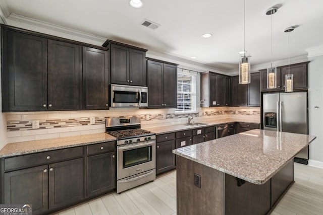 kitchen featuring backsplash, stainless steel appliances, a center island, dark brown cabinetry, and decorative light fixtures