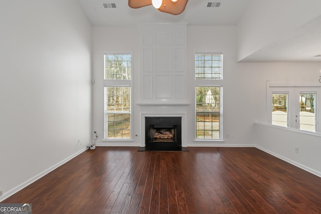 unfurnished living room with a fireplace, dark hardwood / wood-style floors, ceiling fan, and french doors