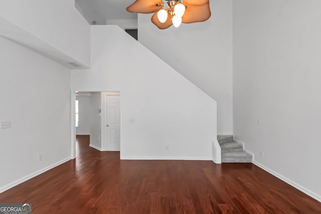 unfurnished living room with dark hardwood / wood-style floors, ceiling fan, and a high ceiling