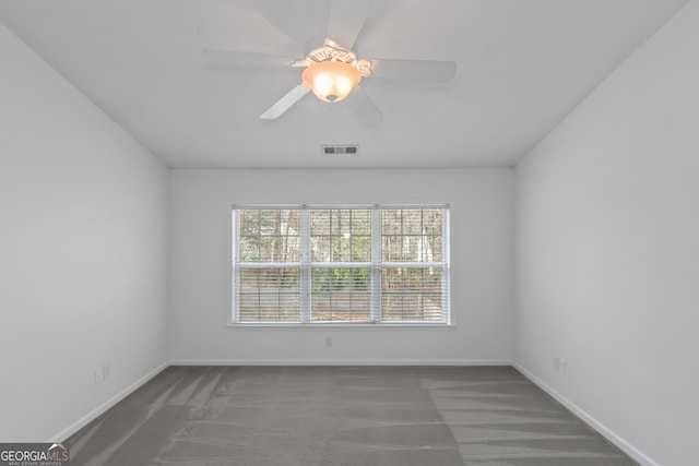 empty room with dark colored carpet and ceiling fan