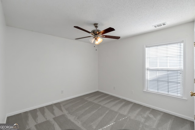 carpeted spare room featuring ceiling fan and a textured ceiling