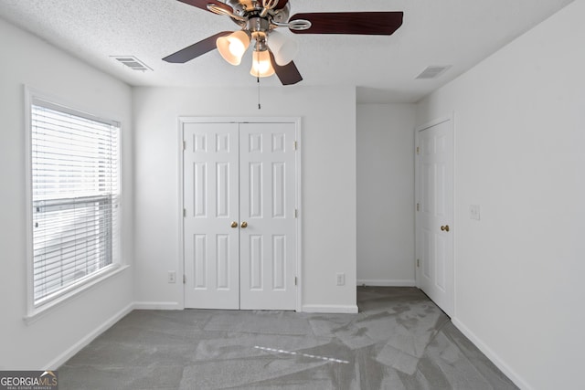 unfurnished bedroom featuring ceiling fan, carpet flooring, a closet, and a textured ceiling