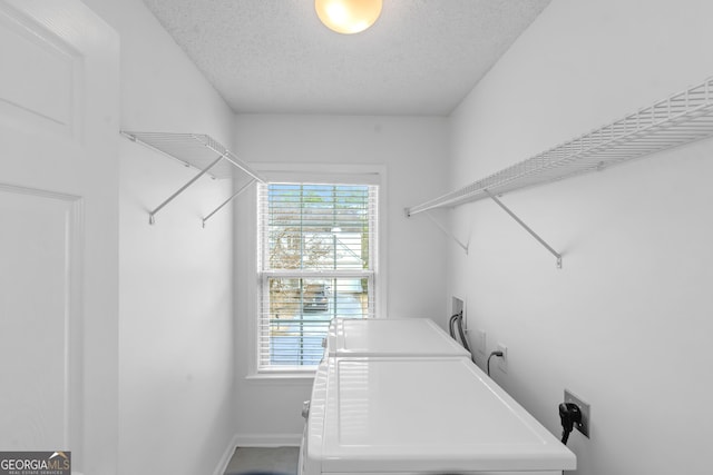 laundry area with a healthy amount of sunlight, washing machine and clothes dryer, and a textured ceiling