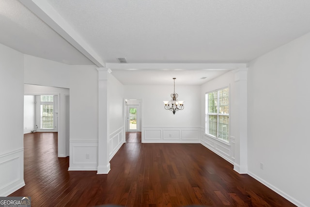 unfurnished room with dark wood-type flooring, a chandelier, beamed ceiling, and ornate columns