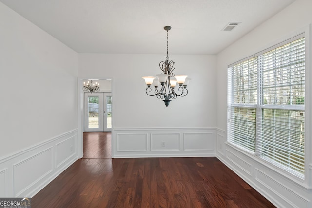 unfurnished dining area with french doors, dark hardwood / wood-style flooring, and a notable chandelier