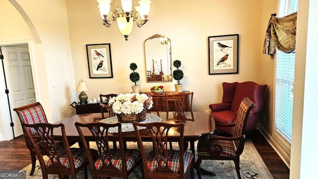 dining room with arched walkways, dark wood-style floors, and a notable chandelier