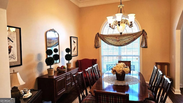 dining space with baseboards, ornamental molding, wood finished floors, and an inviting chandelier