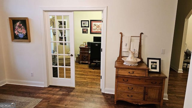 entryway featuring arched walkways, french doors, dark wood finished floors, and baseboards