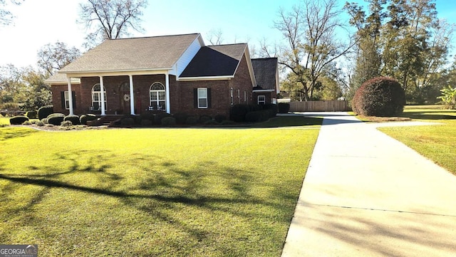 view of side of home featuring brick siding, fence, and a yard