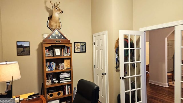 office area featuring dark wood-style floors, arched walkways, and a towering ceiling