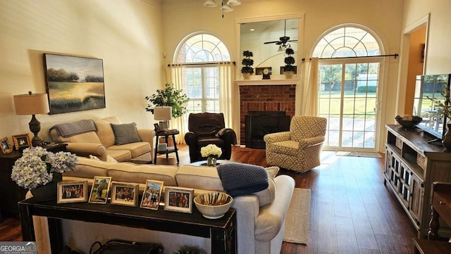 living room featuring ceiling fan, a fireplace, dark wood-style flooring, and a wealth of natural light