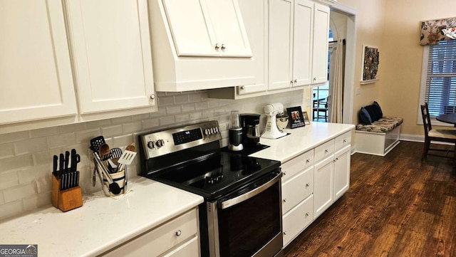 kitchen featuring stainless steel electric range oven, white cabinetry, backsplash, and dark wood-type flooring