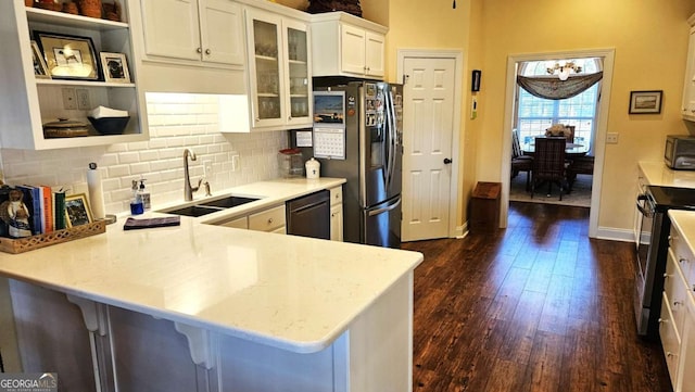 kitchen featuring glass insert cabinets, dark wood-type flooring, a peninsula, black appliances, and a sink