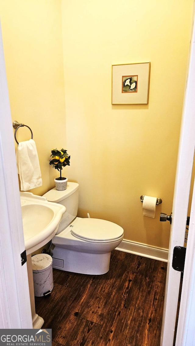 bathroom with a sink, wood finished floors, toilet, and baseboards