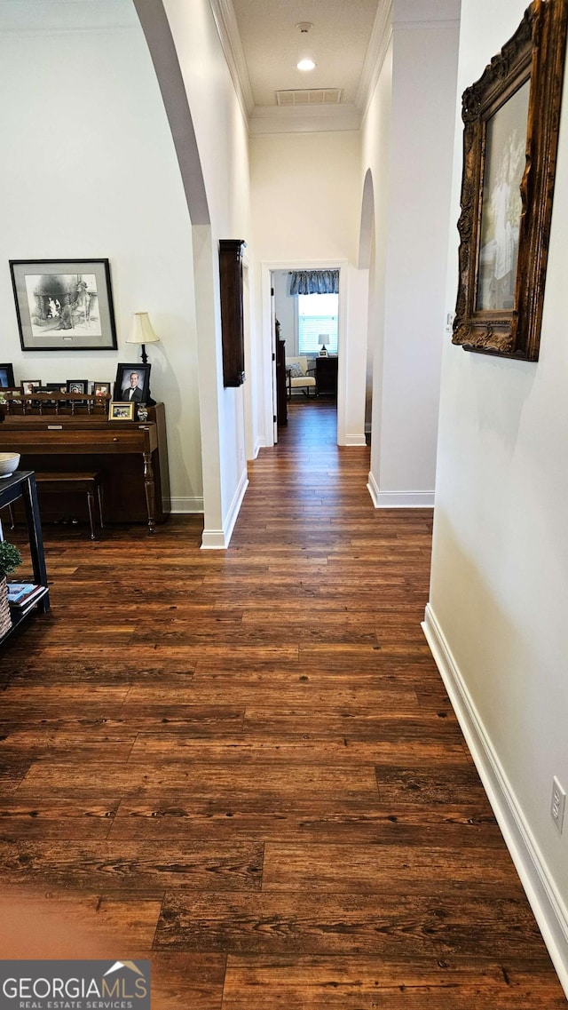 hallway with hardwood / wood-style floors, visible vents, arched walkways, and crown molding