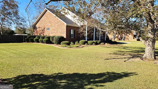 view of home's exterior featuring brick siding, a lawn, and fence