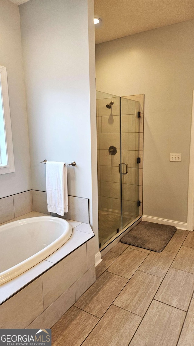 bathroom with a stall shower, baseboards, and a bath