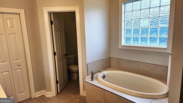 bathroom featuring toilet, a closet, and a bath