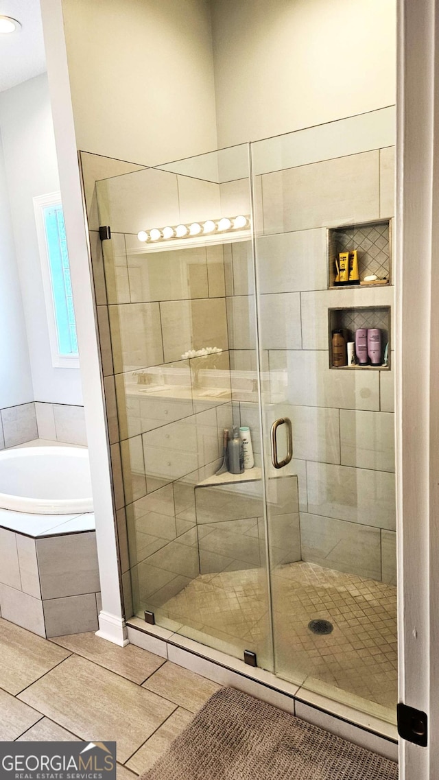 bathroom with a stall shower, tile patterned flooring, and a bath