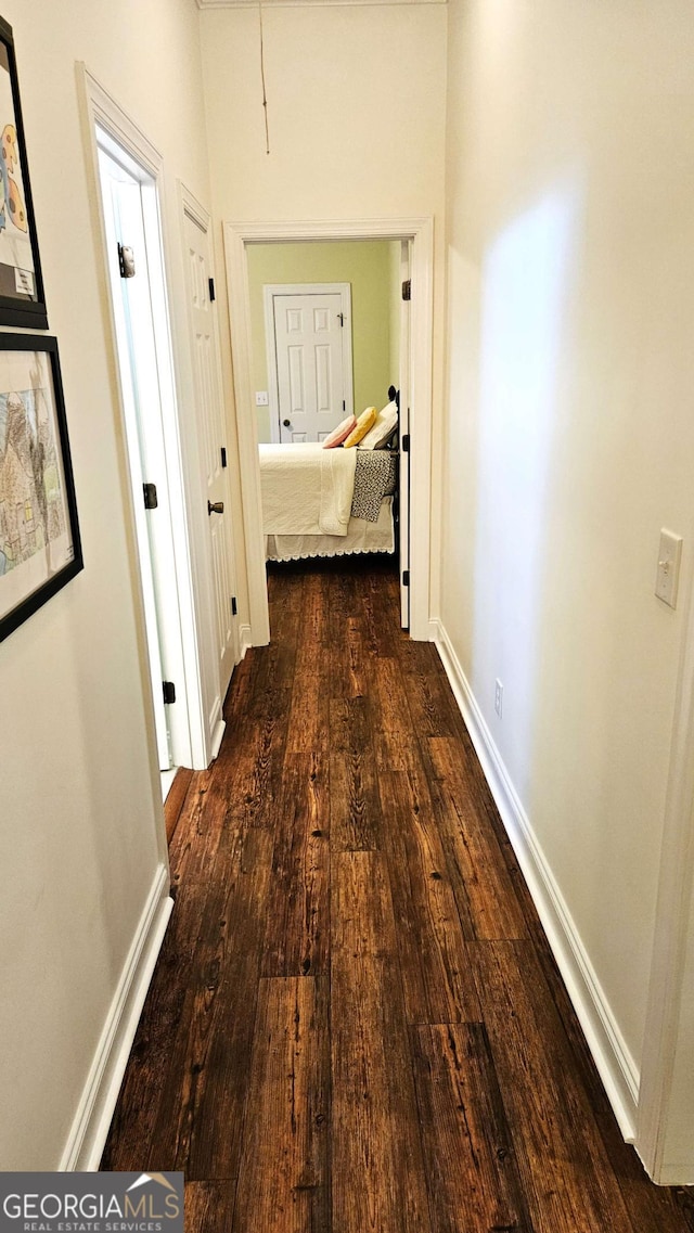 hallway with dark wood-style floors and baseboards