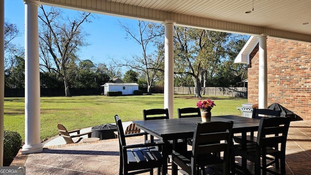 view of patio / terrace with an outbuilding, an outdoor fire pit, fence, a grill, and outdoor dining space