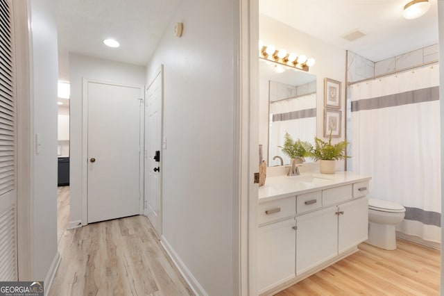 bathroom featuring vanity, hardwood / wood-style flooring, a shower with curtain, and toilet