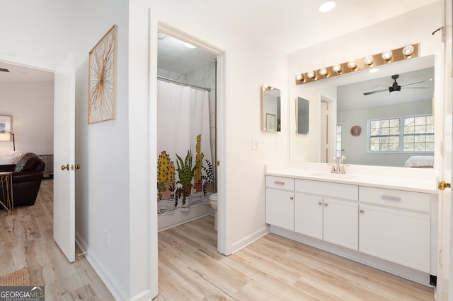 bathroom featuring curtained shower, wood-type flooring, vanity, ceiling fan, and toilet