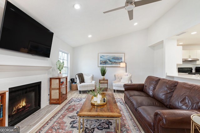 living room featuring ceiling fan, lofted ceiling, and light hardwood / wood-style floors