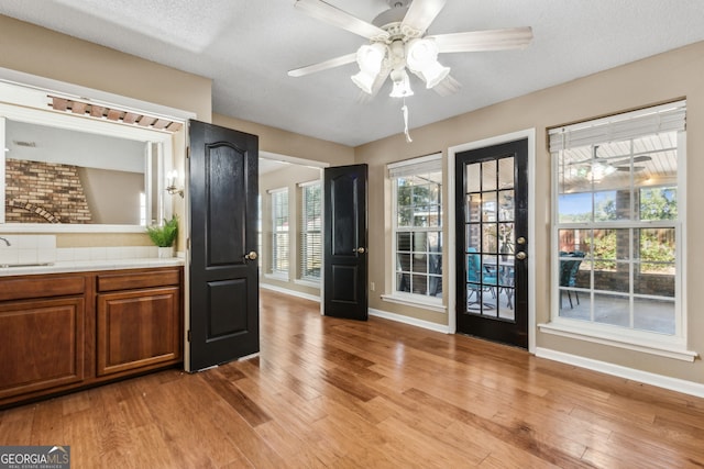 entryway with ceiling fan, sink, a textured ceiling, and light hardwood / wood-style floors