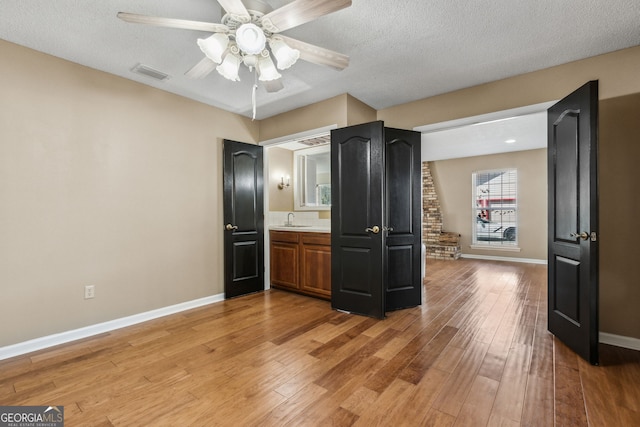 kitchen featuring ceiling fan, sink, a textured ceiling, and light hardwood / wood-style flooring