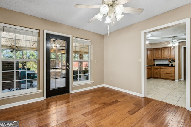 spare room with ceiling fan, a textured ceiling, and light wood-type flooring