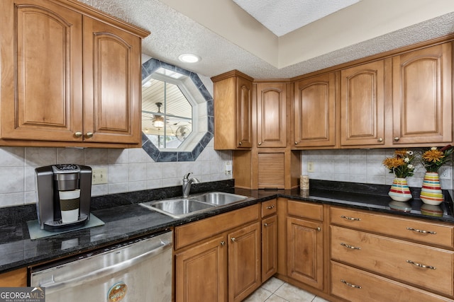 kitchen with sink, dishwasher, dark stone countertops, tasteful backsplash, and light tile patterned flooring