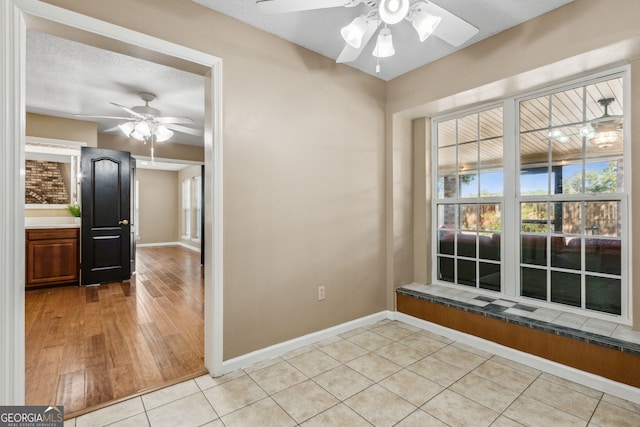 unfurnished room featuring light tile patterned floors, a textured ceiling, and ceiling fan