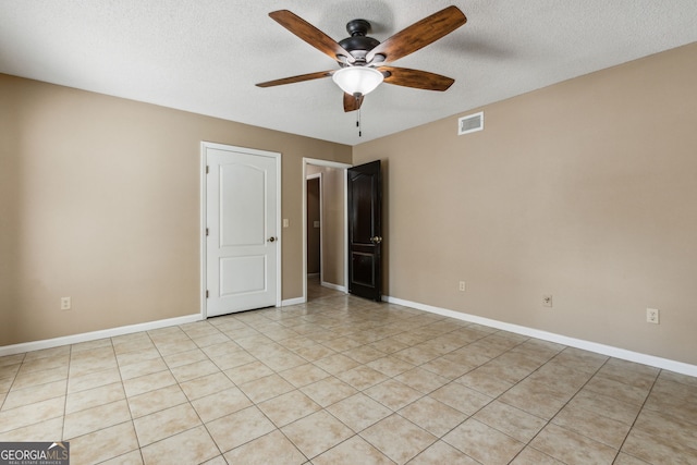 empty room with ceiling fan, light tile patterned flooring, and a textured ceiling