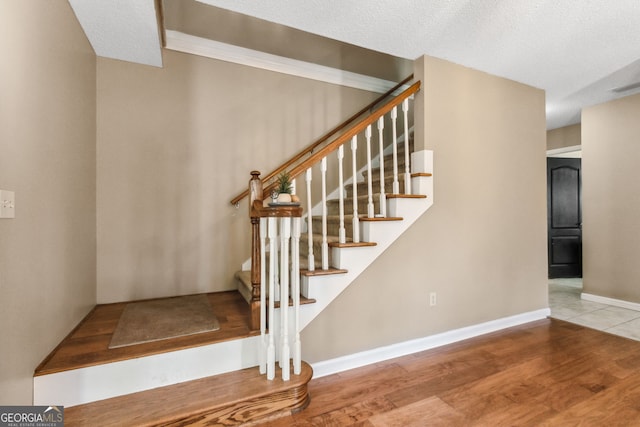 staircase with hardwood / wood-style flooring and a textured ceiling