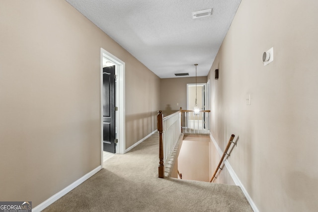 hall featuring light carpet and a textured ceiling