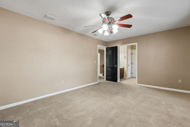 unfurnished bedroom with ceiling fan, light colored carpet, and a textured ceiling