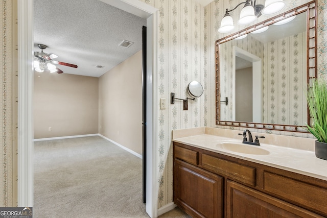 bathroom featuring ceiling fan, vanity, and a textured ceiling