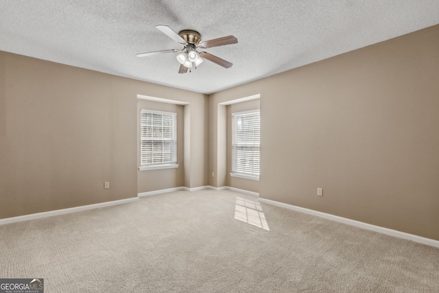 spare room featuring ceiling fan, light colored carpet, and a textured ceiling