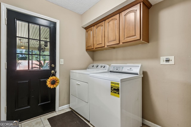 washroom featuring cabinets, independent washer and dryer, a textured ceiling, and light tile patterned floors