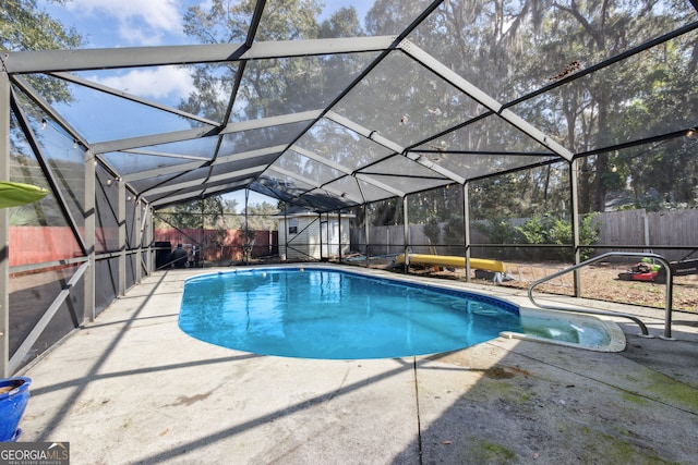 view of pool with a lanai, a patio area, and a storage unit