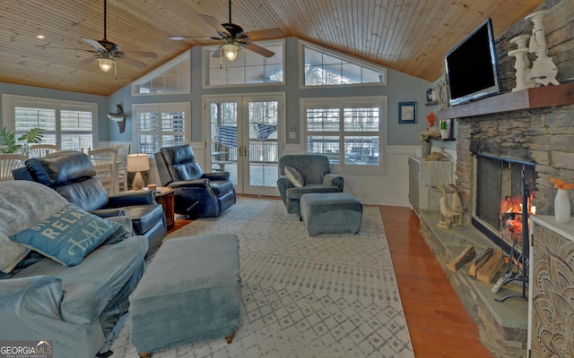 living room featuring wood ceiling, hardwood / wood-style floors, high vaulted ceiling, a stone fireplace, and french doors