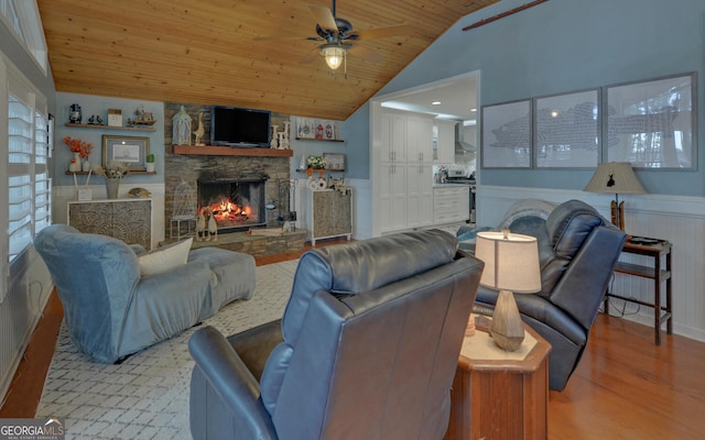 living room featuring high vaulted ceiling, a fireplace, ceiling fan, wood ceiling, and light wood-type flooring